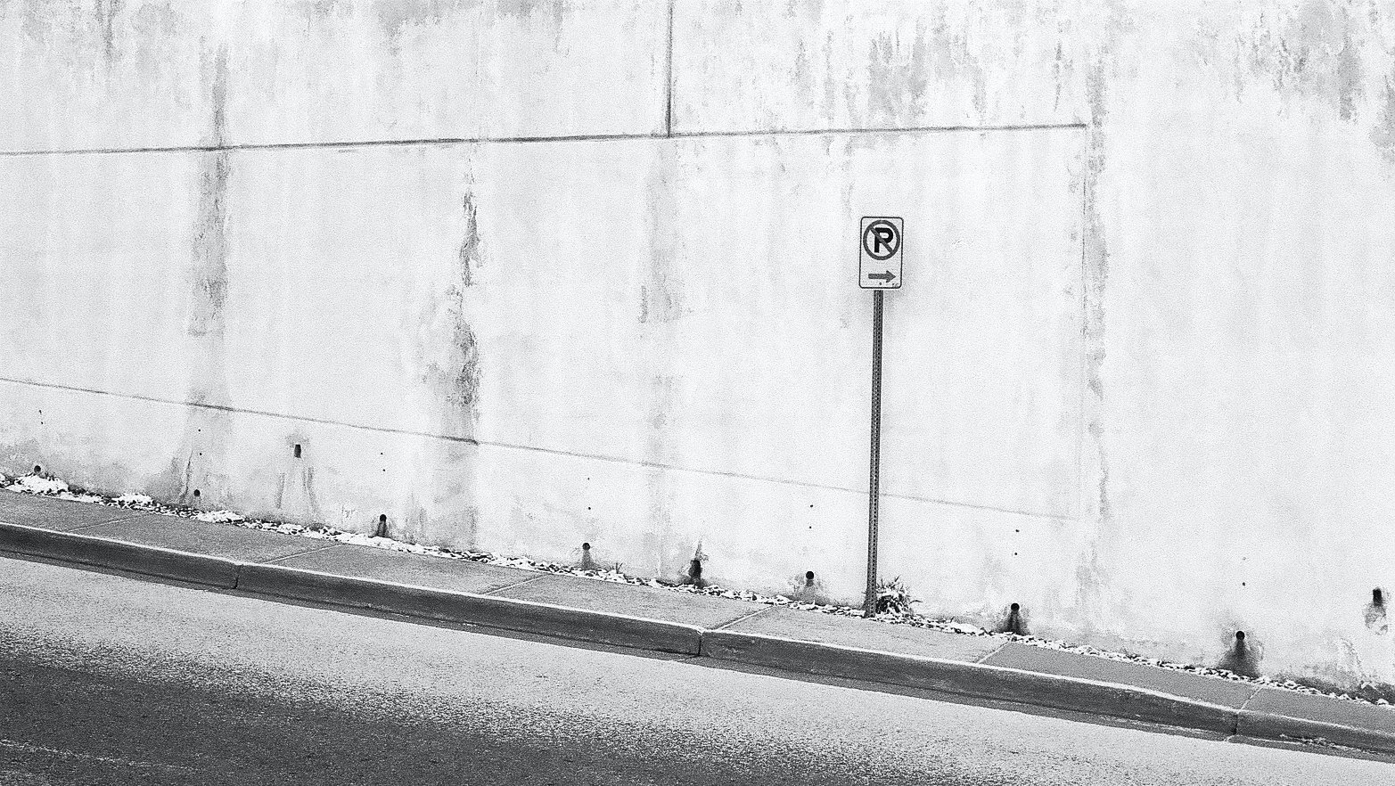 A no parking sign in front of a concrete wall