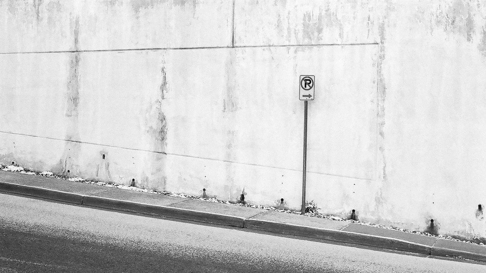 A no parking sign in front of a concrete wall